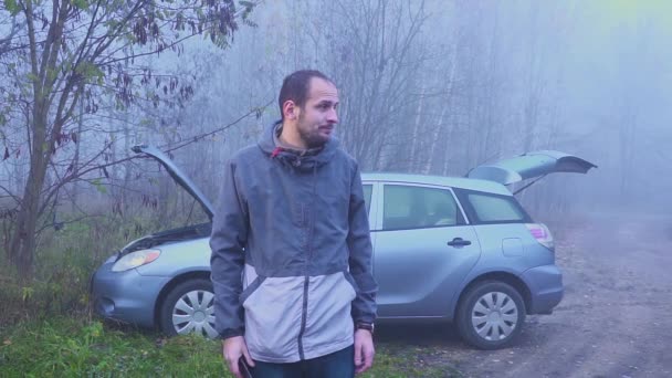 Retrato de hombre triste que de pie cerca de coche roto con capucha abierta — Vídeo de stock