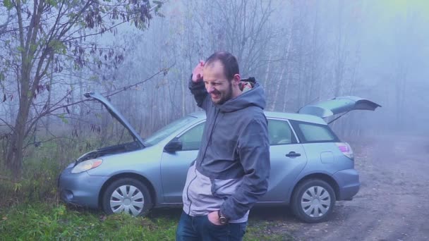 Portret smutny człowiek, który stoi w pobliżu uszkodzony samochód z otworzyć kaptur — Wideo stockowe