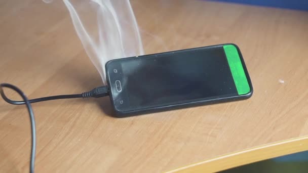 Smartphone è sdraiato sul tavolo e fumare e bruciare. Presto inizierà il fuoco. Concetto di pericolo di incendio. circuito — Video Stock