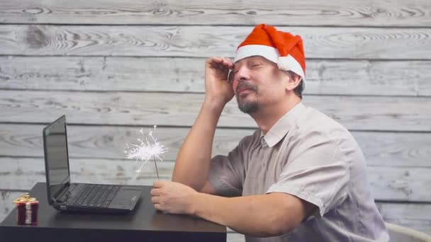 Dromerige man in een kerstmuts met Bengalen brand sparkler en laptop in zijn handen. Dalende dollar van het geld. — Stockvideo