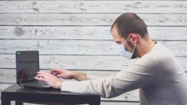 Hasta işadamı sıcaklık ve çalışma office baş ağrısı ile dizüstü bilgisayar kullanın. Öksürük ile yüz maskesi giyen adam.