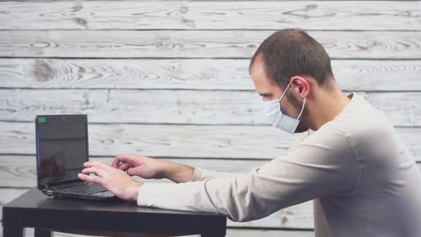 Больной бизнесмен пользуется ноутбуком с температурой и головной болью, работая в офисе. Мужчина в маске с кашлем . — стоковое видео