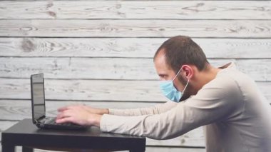 Hasta işadamı sıcaklık ve çalışma office baş ağrısı ile dizüstü bilgisayar kullanın. Öksürük ile yüz maskesi giyen adam.