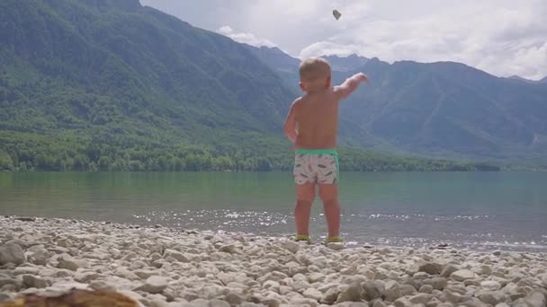 Menino 2 anos na água do lago da montanha da floresta. vista para trás . — Vídeo de Stock