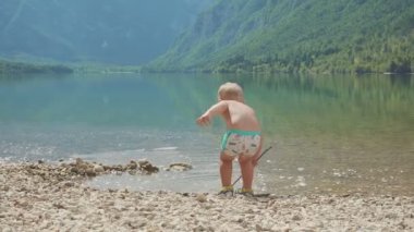 Orman dağ gölü su içindeki küçük çocuk 2 yıl. Arkadan görünüm.