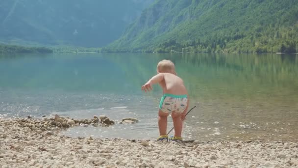 Маленький хлопчик 2 роки у воді лісового гірського озера. вид ззаду . — стокове відео