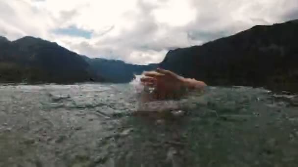 Мужчина брызгает водой в камеру. Улыбающийся человек в замедленной съемке. красивое горное озеро — стоковое видео