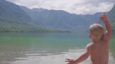Orman dağ gölü su içindeki küçük çocuk 2 yıl. Arkadan görünüm.