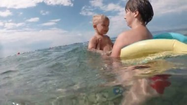 Yüzme ve erkek çocuk çocuk ile deniz ya da okyanus su güneşli bir günde açık doğal artalanda çalışır Genç Anne.