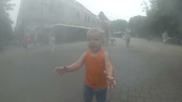 Aufgeregter Junge, der sich zwischen Wasserspritzern im Springbrunnen vergnügt. Sommer in der Stadt — Stockvideo