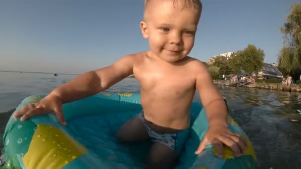 Stadtstrand mit Menschen in der Stadt und Junge schwimmt und spielt im Wasser — Stockvideo