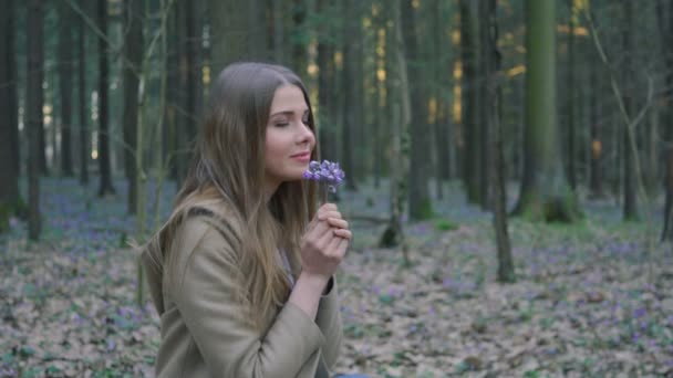 Hermosa joven recoge flores silvestres en el bosque — Vídeos de Stock