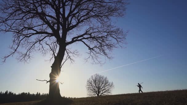 Bauer mit Schaufel auf dem Feld. Sie tragen Geräte, um einen Baum zu pflanzen. am Sonnenuntergang. Seitenansicht — Stockvideo