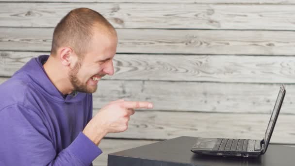Усміхнений чоловік сидить в офісі і працює на ноутбуці — стокове відео
