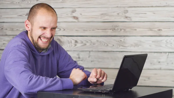 Ofiste oturan ve dizüstü bilgisayarda çalışma gülümseyen adam