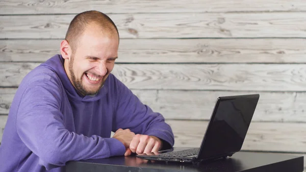 Ofiste oturan ve dizüstü bilgisayarda çalışma gülümseyen adam