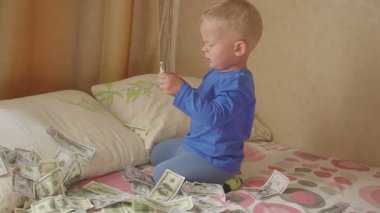 sevimli küçük oğlu yatakta bir doları yağmur altında. Miras kavramı.