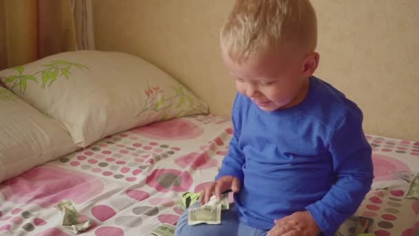 Lindo niño bajo una lluvia de un dólar en la cama. Concepto de patrimonio . — Vídeo de stock