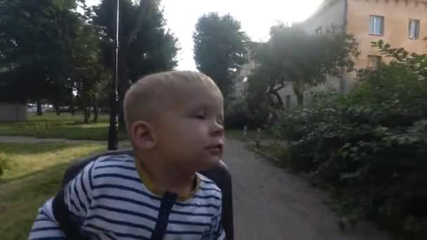 Kind jongen op fiets stoel zitten terwijl rijden en rondkijken — Stockvideo