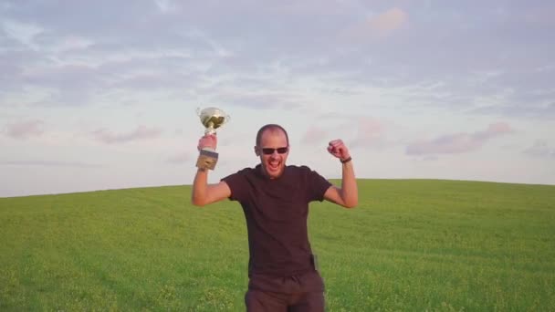 Der Gewinner mit einer Belohnung in der Hand hebt die Hände, genießt den Erfolg. er springt und tanzt — Stockvideo