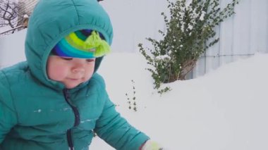 Bir yıl yaşlı erkek çocuk kar bahçede oynuyor.