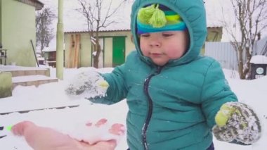Bir yıl yaşlı erkek çocuk kar bahçede oynuyor.
