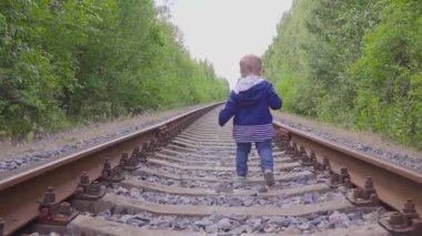 Demiryolu üzerinde yürüyen çocuk. Tehlikeli Oyunlar ve eğlence. Yaz günü.