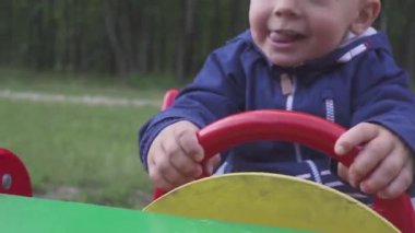 oyuncak araba salıncakta oynarken iki yaşında neşeli bir çocuk. portrite.