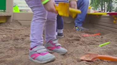 Çocuk oyunları. Kum havuzunda kazma bebeğim. Gülümsüyor ve kum dokunur.