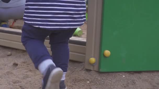 Juegos para niños. Niño cavando en la caja de arena. Sonríe y toca la arena . — Vídeos de Stock