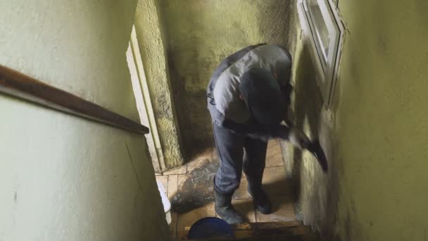 The man cleans the walls of strong dirt with a brush and a rag. The worker washes the corridor walls manually. Mold and dirt. Hard work — Stock Video