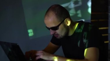 Karanlık bir odada güneş gözlüklü bir adam hacker program kodu ile çalışır. konsepti üzerine siber suçlar