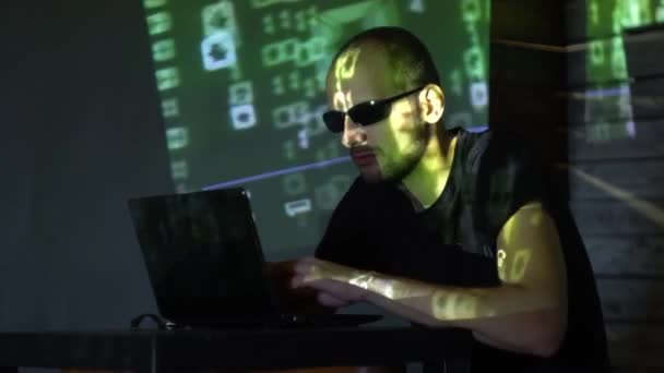 Ein Mann Hacker mit Sonnenbrille in einem dunklen Raum arbeitet mit dem Programmcode — Stockvideo