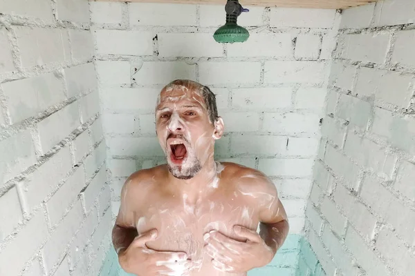 Barbu drôle homme prendre une douche et shampooing sur sa tête dans la salle de bain en brique vintage Photo De Stock