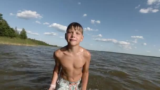 Fröhlicher kleiner Junge, der im Wasser plantscht. Kind hat Spaß im See. — Stockvideo