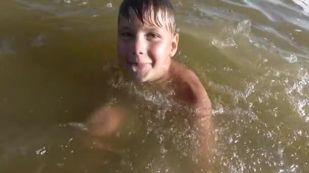 Feliz niño haciendo salpicaduras en el agua. Niño divirtiéndose en el lago . — Vídeo de stock