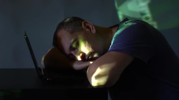 A man hacker in a dark room fell asleep near the computer. works with the program code. concept on cybercrime. — Stock Video