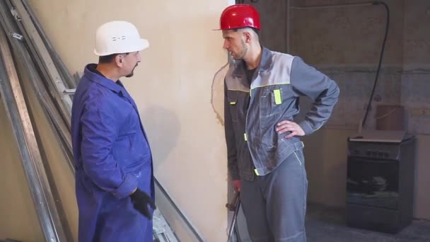 Два строителя обсуждают ремонт помещения — стоковое видео