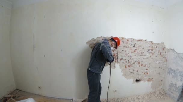 Trabajador en traje protector derriba la pared de yeso. Sucio, trabajo duro. Equipo de protección personal. Casco, respirador y gafas . — Vídeo de stock