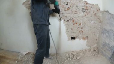 işçi koruyucu kıyafetli alçı duvar yıkan. Kirli, zor iş. Kişisel koruyucu donanım. Kask, maske ve gözlük.