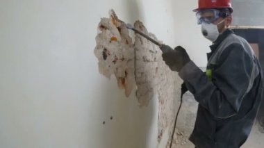 işçi koruyucu kıyafetli alçı duvar yıkan. Kirli, zor iş. Kişisel koruyucu donanım. Kask, maske ve gözlük.