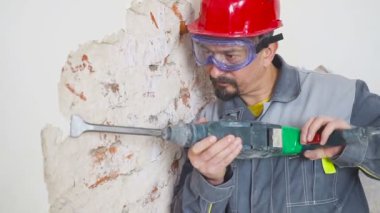 işçi koruyucu kıyafetli alçı duvar yıkan. Kirli, zor iş. Kişisel koruyucu donanım. Kask, maske ve gözlük.