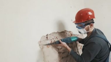 işçi koruyucu kıyafetli alçı duvar yıkan. Kirli, zor iş. Kişisel koruyucu donanım. Kask, maske ve gözlük.