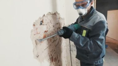 işçi koruyucu kıyafetli alçı duvar yıkan. Kirli, zor iş. Kişisel koruyucu donanım. Kask, maske ve gözlük.