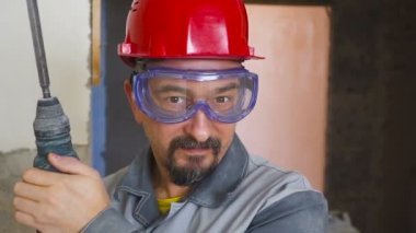 kafasında ve elinde bir perforator ile bir kask içinde yetişkin bir adam portresi