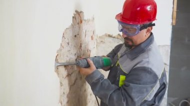 işçi koruyucu kıyafetli alçı duvar yıkan. Kirli, zor iş. Kişisel koruyucu donanım. Kask, maske ve gözlük.