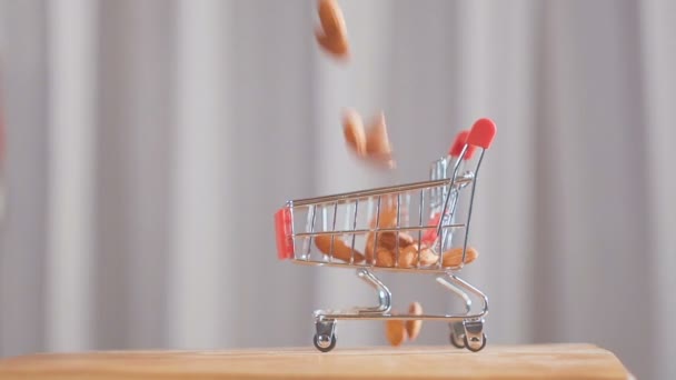 Einkaufswagen aus dem Supermarkt, gefüllt mit Mandelnüssen. Mandelnüsse fallen in den Einkaufswagen. — Stockvideo
