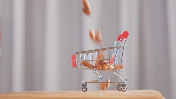 Carrello della spesa dal supermercato pieno di noci di mandorle. noci di mandorla cadono nel carrello del supermercato . — Video Stock