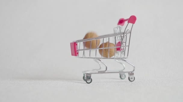 Shopping cart from the supermarket filled with walnuts nuts. walnuts fall in the supermarket cart. — Stock Video