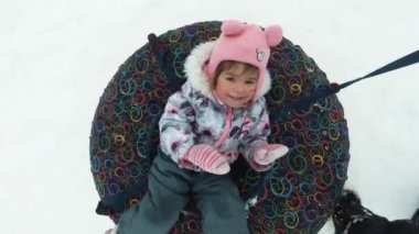 kış, boş zaman ve eğlence kavramı - bir kızağa yalan ve hareketi sırasında sallayarak mutlu küçük kız.